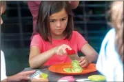  ?? NWA Democrat-Gazette/J.T. WAMPLER ?? Sofia Martinez-Carballal cuts green tomatoes July 11 during the Yvonne Richardson Community Center’s Kid Crops program. An outdoor garden shelter is planned for the center, thanks to a combinatio­n of grant funding and volunteer contributi­on. Children taking part in the center’s Kid Crops program will be able to use the shelter to learn about gardening, cook and wash food and store equipment.