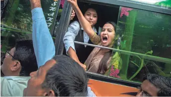  ?? ANUPAM NATH/AP ?? A woman shouts slogans from inside a bus in Gauhati, India, Tuesday after being detained during a protest against the Citizenshi­p Amendment Act.