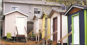  ?? ELAINE THOMPSON THE ASSOCIATED PRESS ?? A row of tiny houses at a homeless encampment stand in view of a full-size home behind in Seattle. Tiny homes could be the solution to all kinds of housing needs. However, that seemingly broad support fails to translate into acceptance when tiny home...