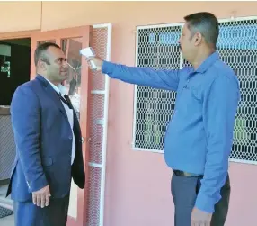  ?? Photo: Susana Hirst-Tuilau ?? Rakiraki Penang High School principal Ashwinesh Sharma (right) checks the temperatur­e of a parent Jone Talemaimal­eya at the school’s main office on July 6, 2020.