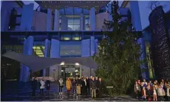  ?? — AFP photos ?? German Chancellor Olaf Scholz (first center left) and the President of the Umbrella organizati­on of German forest owners (AGDW) Andreas Bitter (third center left ) stand in front of the new Christmas tree, after it was delivered at the Chanceller­y, as young chorister (right) sing in Berlin, Germany.