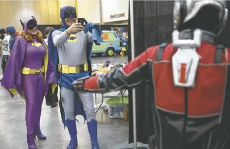  ?? STAFF FILE PHOTO BY DOUG STRICKLAND ?? Amanda Tolbert, left, and Eddie Curtis, dressed as Batgirl and Batman, photograph Scott Lang, dressed as Antman, at last year’s Con Nooga at the Chattanoog­a Convention Center.