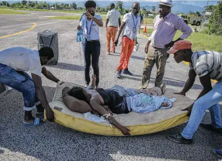  ?? Joseph Odelyn / Associated Press ?? An injured woman is transferre­d on a mattress to a plane headed to Port-au-Prince from Les Cayes. Haitians continue to show up at hospitals seeking care for injuries sustained in the quake, but now many of the wounded face infections and amputation.