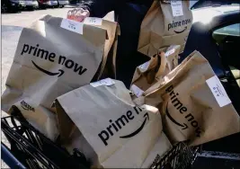  ?? ASSOCIATED PRESS ?? AMAZON PRIME NOW bags full of groceries are loaded for delivery by a part-time worker outside a Whole Foods store Thursday in Cincinnati. Amazon, which owns Whole Foods, plans to roll out two-hour delivery at the organic grocer this year to those who pay for Amazon’s $99-a-year Prime membership. Amazon.com Inc. said deliveries started Thursday in Austin, Texas; Cincinnati; Dallas; and Virginia Beach, Va.