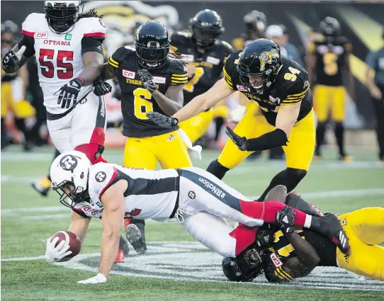  ?? PETER POWER/THE CANADIAN PRESS ?? Redblacks fullback Patrick Lavoie is tackled by Tiger-Cats linebacker Larry Dean after making a reception on Friday night in Hamilton.