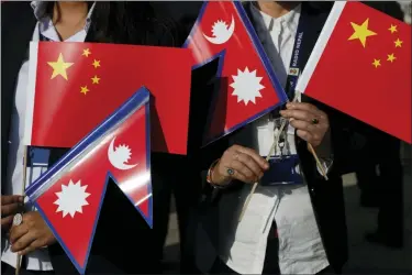  ?? NIRANJAN SHRESTHA — THE ASSOCIATED PRESS ?? Government officers hold Chinese and Nepalese flag as they wait to welcome Chinese president Xi Jinping in Kathmandu, Nepal, Saturday. Xi has become the first Chinese president in more than two decades to visit Nepal, where he’s expected to sign agreements on major infrastruc­ture projects.