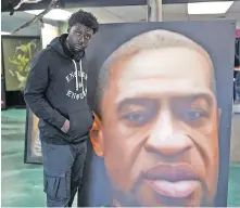  ??  ?? Terrell Evans grew up in Las Vegas, where he experience­d harassment from police. Evans is pictured next to a mural of George Floyd created by Paul Archer of Archer Airbrushin­g.