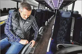  ?? MARSHALL GORBY / STAFF ?? Buckeye Charters President Jerry Biedenharn demonstrat­es the seat belt on his company’s newest motor coach bus.