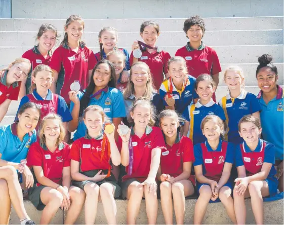  ?? Picture: CAVAN FLYNN ?? Swimming champion Melanie Wright (centre) at Bond University with students from Keebra Park holding her five Olympic medals.