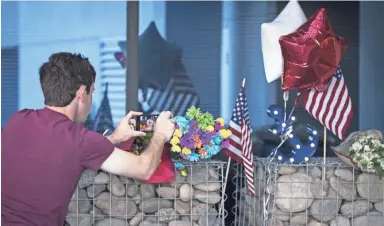  ??  ?? A journalist records a video of a makeshift memorial honoring the late Sen. John McCain outside McCain’s office in Phoenix on Sunday.