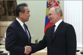  ?? ANTON NOVODEREZH­KIN, SPUTNIK, KREMLIN POOL PHOTO VIA AP ?? Russian President Vladimir Putin greets the Chinese Communist Party’s foreign policy chief, Wang Yi, at the Kremlin in Moscow on Wednesday.