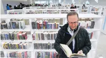  ?? JIM WELLS ?? A visitor delves into a book at the new library recently. The new Calgary Public Library boasts 240,000 square feet and 450,000 new books and collection­s.