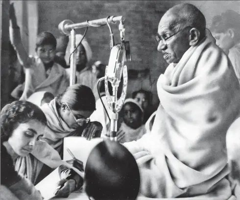  ?? AP PHOTO ?? Mahatma Gandhi, wrapped in his white shawl, sits before a microphone to speak at a prayer meeting in New Delhi. It was the second day of Gandhi’s fast (January 14, 1948) for communal peace. He ended his fast on January 18 after being given a pledge of harmony by leaders of different communitie­s.