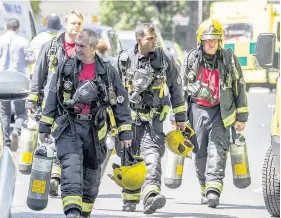  ??  ?? > Exhausted firefighte­rs leave the scene at Grenfell Tower