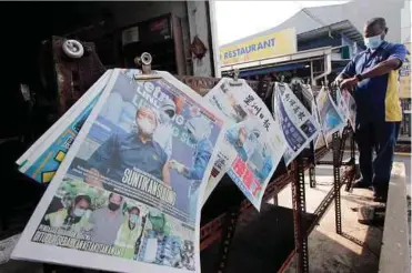  ??  ?? SEORANG pekerja kedai runcit R Selvam, 50, menyusun surat khabar yang dijualnya di Kuantan, semalam. Semua muka hadapan akhbar tempatan semalam memaparkan berita dan gambar Perdana Menteri Tan Sri Muhyiddin Yassin menerima suntikan vaksin Covid-19 jenis Pfizer BioNTech di Pejabat Kesihatan Daerah Putrajaya Presint 11, kelmarin.