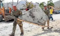  ??  ?? British soldiers help to clear debris in Tortola, in the British Virgin Islands, where about 100 convicts are on the loose after Irma damaged the local jail.