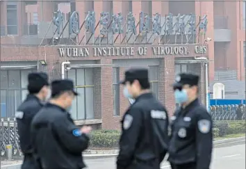  ?? Hector Retamal AFP/Getty Images ?? SECURITY personnel stand guard outside the Wuhan Institute of Virology in Wuhan as members of the World Health Organizati­on team visit the Chinese lab during an investigat­ion in February 2021.