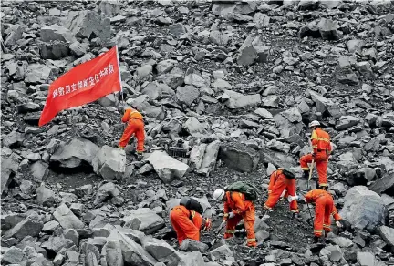  ?? PHOTO: REUTERS ?? Rescue workers search for survivors at the site of a landslide in Xinmo Village, Mao County, Sichuan province. The writing on the flag reads: ‘‘Chengdu Fire Departmant Rescue Team’’.