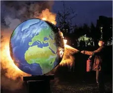  ?? /Bloomberg/File ?? Putting out flames: An environmen­tal activist extinguish­es a burning model of the Earth during a climate protest over the European Central Bank‘s funding of fossil fuels, outside the bank’s headquarte­rs in Frankfurt, Germany.