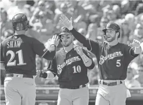  ??  ?? From left, Travis Shaw, Yasmani Grandal and Cory Spangenber­g celebrate after scoring on a three-run double by Orlando Arcia.