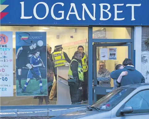  ?? Picture: Paul Reid. ?? A woman is consoled outside the betting shop as police officers investigat­e inside.