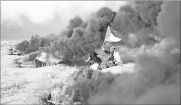  ?? — AFP photo ?? A Palestinia­n woman waves a national flag near burning tyres during clashes along the Israeli border fence, east of Gaza City.