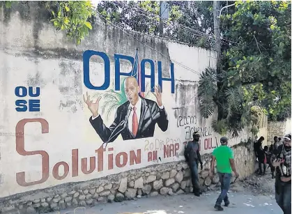  ?? REUTERS ?? People walk past a wall with a mural depicting Haiti’s President Jovenel Moise, after he was shot dead by unidentifi­ed attackers in his private residence, in Port-au-Prince, Haiti on Wednesday.