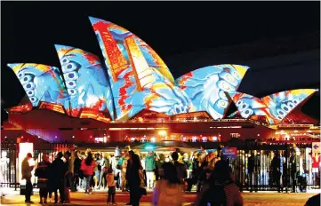  ??  ?? Members of the public watch as the Sydney Opera House is illuminate­d during the opening night of the Vivid Sydney festival of light and sound in Australia. — Reuters photo