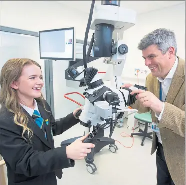 ??  ?? Fundraisin­g East Kilbride schoolgirl Jenny Cook takes a look at the surgical microscope