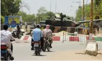  ?? (Oredje Narcisse/Reuters) ?? PEOPLE DRIVE PAST a Chad army tank near the presidenti­al palace in N’djamena on Tuesday.