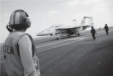  ?? Jon Gambrell, The Associated Press ?? In this June 3 photo, a crew member looks at a taxiing F/A-18 fighter jet on the deck of the USS Abraham Lincoln aircraft carrier in the Persian Gulf. The U.S. aircraft carrier the White House ordered to the Mideast over a perceived threat from Iran remains outside of the Persian Gulf amid efforts to de-escalate tensions between Tehran and Washington.