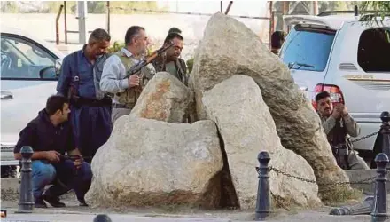  ??  ?? Peshmerga fighters sheltering behind rocks
Reuters pic