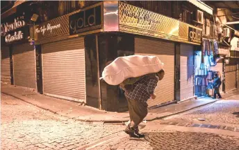  ?? — AFP photo ?? A porter carries belongings on a street early morning near Grand bazaar in Istanbul.
