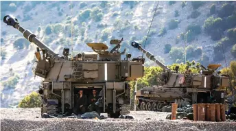  ??  ?? Israeli soldiers sit in the back of a self-propelled artillery gun positioned along the border with Syria in the the Israeliann­exed Golan Heights.