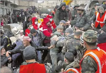  ?? Omar Sanadiki Associated Press ?? CIVIL DEFENSE workers and security forces in Hama, Syria, carry a victim of the 7.8 earthquake Monday in southeaste­rn Turkey. Tens of thousands left homeless by the early morning disaster faced a night in the cold.