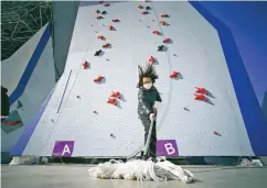  ?? EUGENE HOSHIKO/ASSOCIATED PRESS ?? A member of the Tokyo 2020 Olympic Games organizing staff mops the floor in front of the climbing wall Friday in the test event of Speed Climbing in preparatio­n for the Summer Games at Aomi Urban Sports Park in Tokyo.