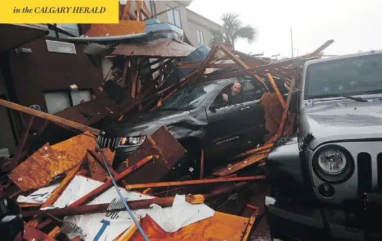  ?? GERALD HERBERT / THE ASSOCIATED PRESS ?? A storm chaser retrieves equipment from his vehicle during a brief calm in the eye of Hurricane Michael after a hotel canopy collapsed in Panama City Beach, Fla., Wednesday.