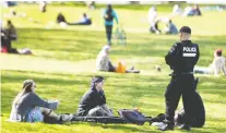  ?? ALLEN MCINNIS ?? An SPVM officer talks to people gathered at Jeanne-mance Park in May. Quebec accounted for 77 per cent of reported fines in Canada for violating public health orders during the COVID-19 pandemic.