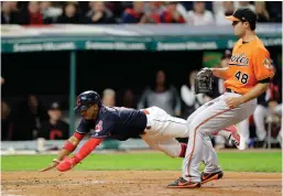  ?? Associated Press ?? n Cleveland Indians' Francisco Lindor, left, scores on a wild pitch by Baltimore Orioles relief pitcher Richard Bleier, right, in the seventh inning of a baseball game Friday in Cleveland.