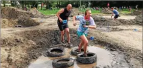  ??  ?? Runners high-step it across tires in a muddy pit during the Tuff eNuff Challenge.