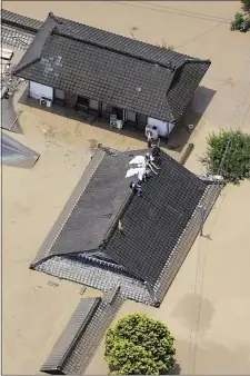  ?? KYODO NEWS VIA AP ?? Residents are stranded on the rooftop of a house submerged in muddy waters that gushed out from the Kuma River in Hitoyoshi, Kumamoto prefecture, southweste­rn Japan, Saturday, July 4. Heavy rain triggered flooding and mudslides on Saturday, leaving more than a dozen missing. More than 75,000residen­ts in the prefecture­s of Kumamoto and Kagoshima were asked to evacuate following pounding rains overnight.