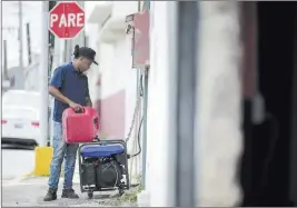  ?? Carlos Giusti ?? The Associated Press Juan Castro fills a generator with gasoline Wednesday to energize the cabinet building workshop where he works in San Juan, Puerto Rico.