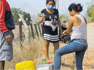  ??  ?? Habitantes vigilan que si alguien va a entrar a la vereda se lave las manos antes.