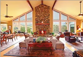  ??  ?? Windows on either side of the floor-to-ceiling river rock fireplace frame unobstruct­ed river and mountain views.