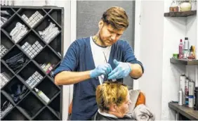  ?? BRENDAN HOFFMAN/THE NEW YORK TIMES ?? Yevgeny Kaseyev, a hairdresse­r, works on a client’s hair in Kiev, Ukraine.