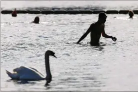  ?? TOLGA AKMEN / AFP / GETTY IMAGES ?? Bathers swim in the Serpentine Lido in Hyde Park, London, on May 19. On web pages giving pandemic advice, the federal Centers for Disease Control say, “There is no evidence that the virus that causes COVID-19 can be spread to people through the water in pools, hot tubs, spas or water play areas.”