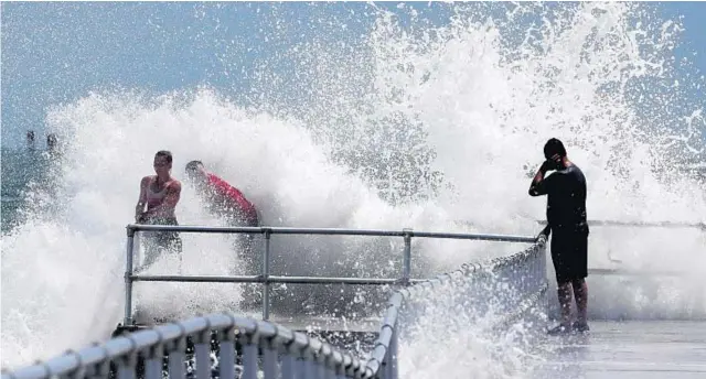  ?? PHOTOS BY JOE BURBANK/ORLANDO SENTINEL ?? Residents hang on to the railing as a wave generated by Hurricane Dorian explodes into the jetty at Lighthouse Point Park in Ponce Inlet on Sept. 2, 2019. Dorian largely missed the state.