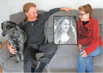  ?? MIKE DE SISTI / MILWAUKEE JOURNAL SENTINEL ?? Jeff and his wife, Sue Shesto, and their dog, Trigger, sit with a photo of their daughter, Sophie, that was on display at Sophie's memorial service after she died of a heroin overdose on June 28, 2015, at their home in Milwaukee.