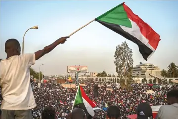  ??  ?? A Sudanese protester waves the national flag during a rally outside the army complex in Khartoum. — AFP photo