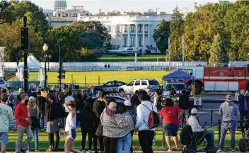  ?? J. Scott Applewhite / Associated Press ?? People look toward the White House on Friday as Marine One waits to carry President Donald Trump to Walter Reed Hospital, which Texas doctors said was a sign his case may be more serious than was thought.